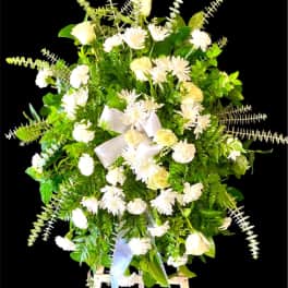 White flowers and greenery arranged on a standing easel with a ribbon