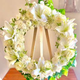 White floral wreath with lilies and roses on a wooden easel