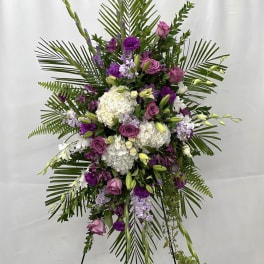 Standing floral spray with purple and white flowers on a tripod easel