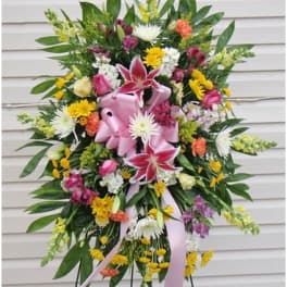 Standing floral spray with pink lilies and mixed blooms on a ribboned easel
