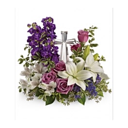 Purple and white floral arrangement with roses and lilies tied with a silver ribbon
