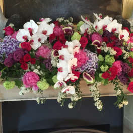 Large floral mantel arrangement with orchids, roses, and hydrangeas