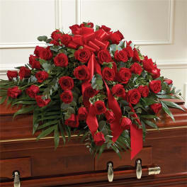 Red rose casket spray with red ribbons on a wooden casket