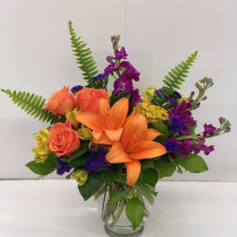 Orange lilies and coral roses in a clear glass vase