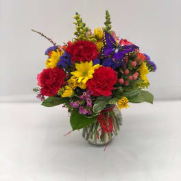 Colorful mixed bouquet in a clear glass vase with a butterfly pick