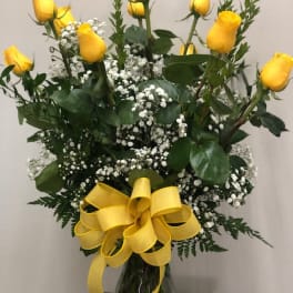 Yellow roses with baby's breath in a glass vase and yellow ribbon