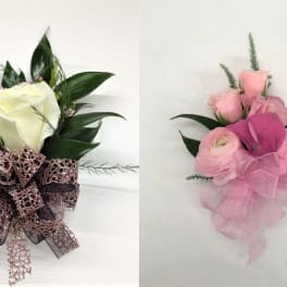 Two corsages with white and pink roses accented with decorative ribbons