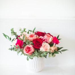 Pink and red roses arranged in a white vase