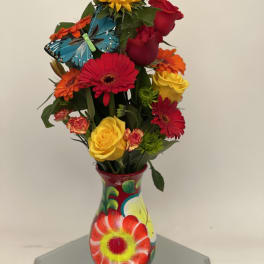 Colorful bouquet of roses, gerbera daisies, and a sunflower in a painted vase