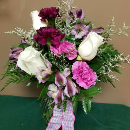 Bouquet of white roses, pink carnations, and purple alstroemeria in a glass vase