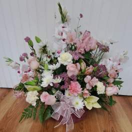 Pink and white mixed flower arrangement in a low basket with a ribbon bow