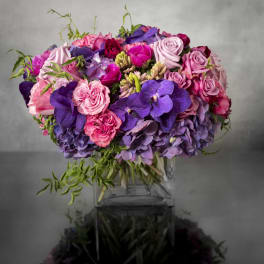 Bouquet of pink and purple roses with hydrangeas in a clear vase