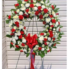Large red and white floral wreath on a stand with a red bow