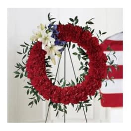 Red floral wreath on a stand with white lilies and blue accents