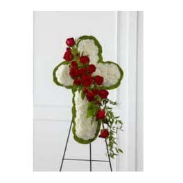 Cross-shaped floral tribute with red roses and white flowers on an easel