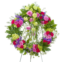 Colorful floral wreath with pink roses, green carnations, and purple flowers