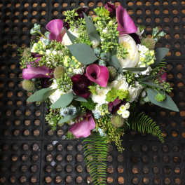 Bouquet of purple calla lilies and white blooms with greenery