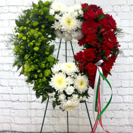 Heart-shaped floral wreath in red, white, and green on a stand