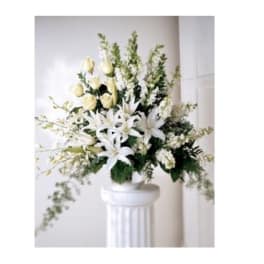 White floral arrangement in a pedestal vase with lilies and roses