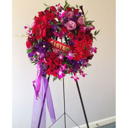 Large red and purple floral wreath on a stand with ribbon