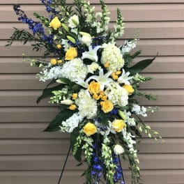 Standing floral spray with white lilies, yellow roses, and blue flowers