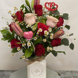 Bouquet of red roses, pink lilies, and daisies in a white vase