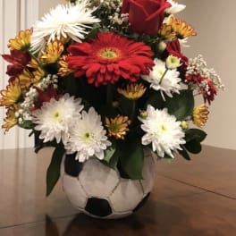 Bouquet of red roses and white daisies in a soccer ball vase