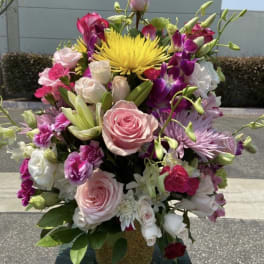 Tall bouquet of pink and white roses with purple orchids and a yellow bloom