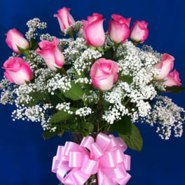 Pink roses with white baby's breath in a glass vase and pink bow