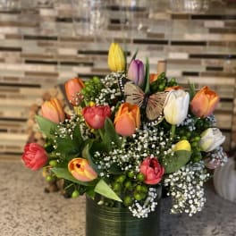 Colorful tulips arranged in a green vase with a butterfly accent