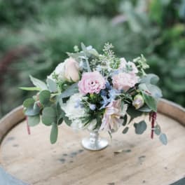 Small pastel floral arrangement in a silver pedestal vase