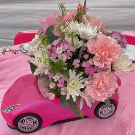 Pink and white bouquet arranged in a pink toy car