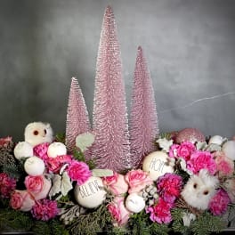 Pink floral arrangement with decorative trees, owls, and white ornaments