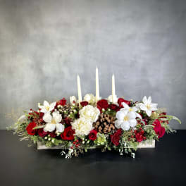 Low floral centerpiece with red and white roses and three white taper candles