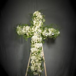 Large floral cross of white roses and hydrangeas on a wooden easel