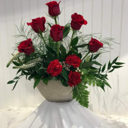 Red roses and carnations arranged in a gray bowl vase