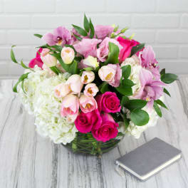 Pink and white mixed bouquet in a glass vase beside a small book