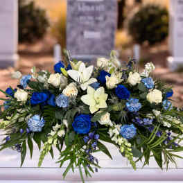 Blue and white floral casket spray with roses and lilies