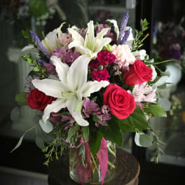 Bouquet of white lilies, red roses, and pink flowers in a glass vase