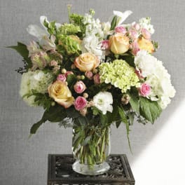 Mixed bouquet of roses, hydrangeas, and white blooms in a glass vase