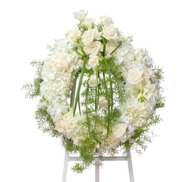 White floral wreath with roses and hydrangeas on a stand