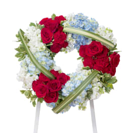 Heart-shaped floral wreath with red roses, blue hydrangeas, and white flowers