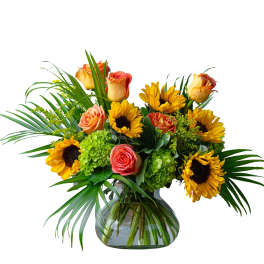Bouquet of sunflowers and peach roses in a glass vase