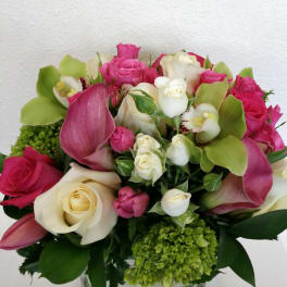 Pink and white roses with green orchids in a glass vase