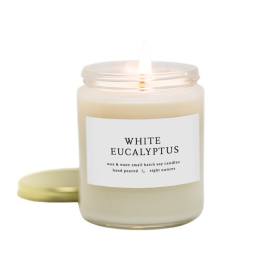Lit white eucalyptus candle in a glass jar with a gold lid