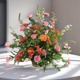 Mixed pink and orange flowers in a low basket arrangement