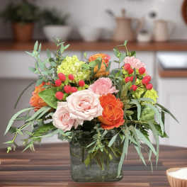 Mixed bouquet of pink and orange roses in a square glass vase