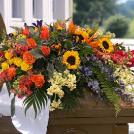 Large mixed floral casket spray with sunflowers, roses, and lilies