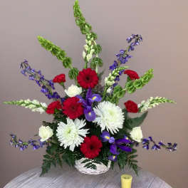 Red, white, and purple flowers in a white basket arrangement