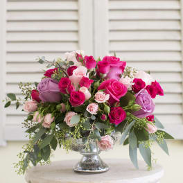 Pink and lavender roses arranged in a silver pedestal vase